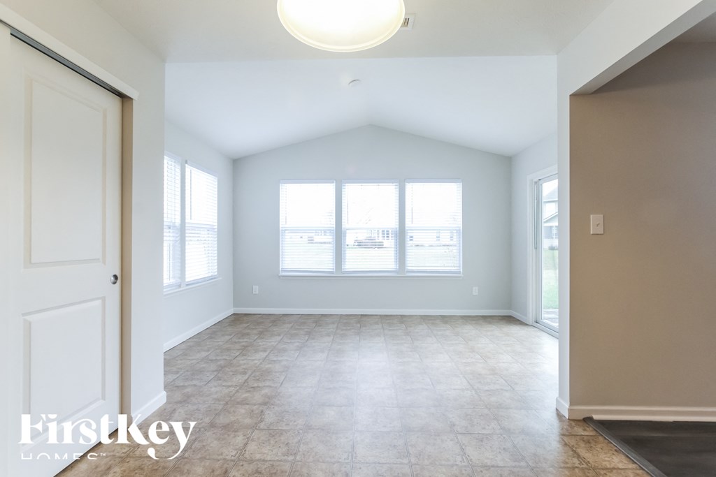 A spacious room with a white door and a window with blinds.