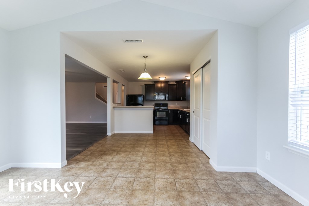 A spacious room with a kitchen area in the background.