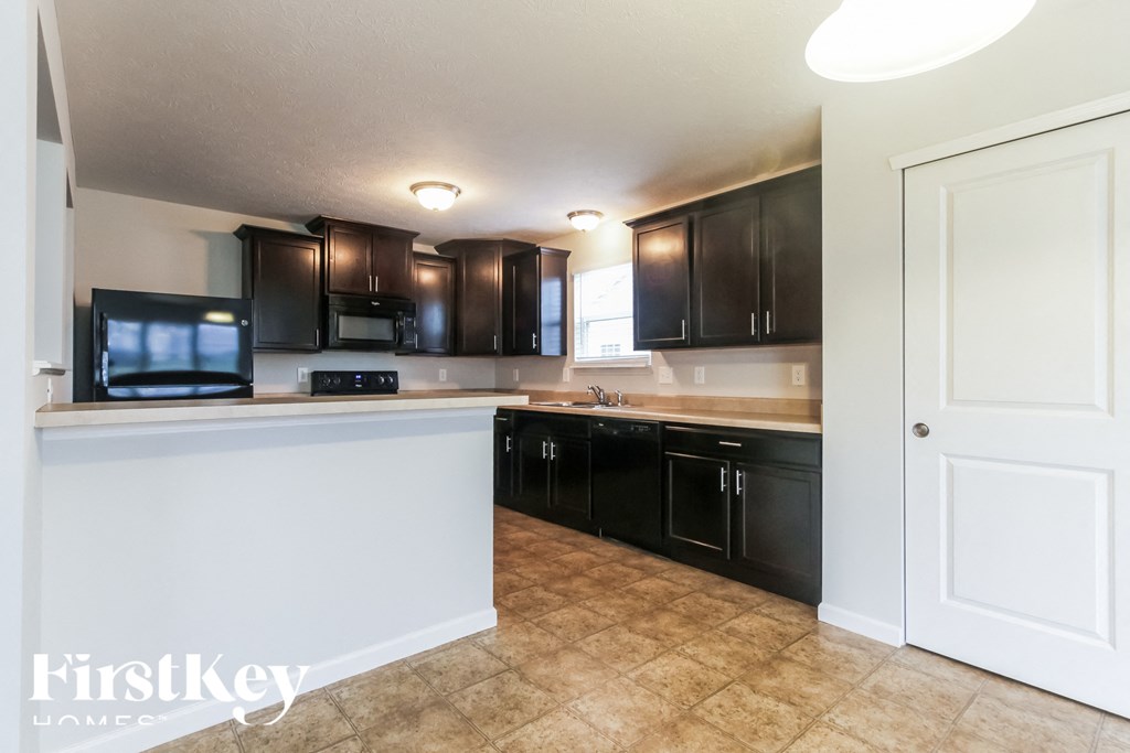 A kitchen with black cabinets and a white counter.
