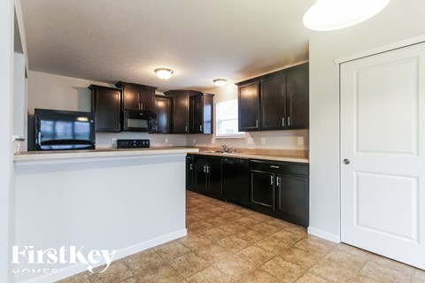A kitchen with black cabinets and a white counter.