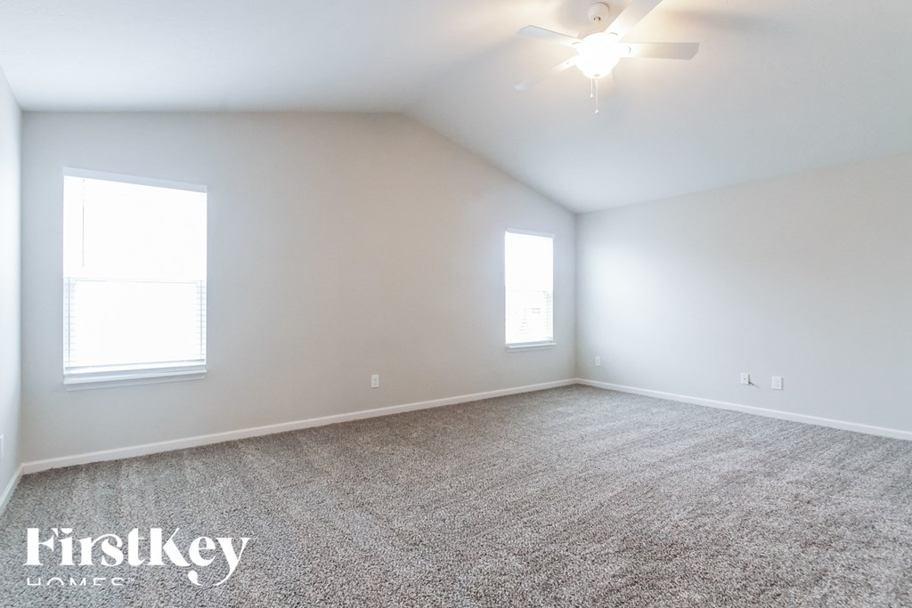 A spacious room with a carpeted floor and two windows.
