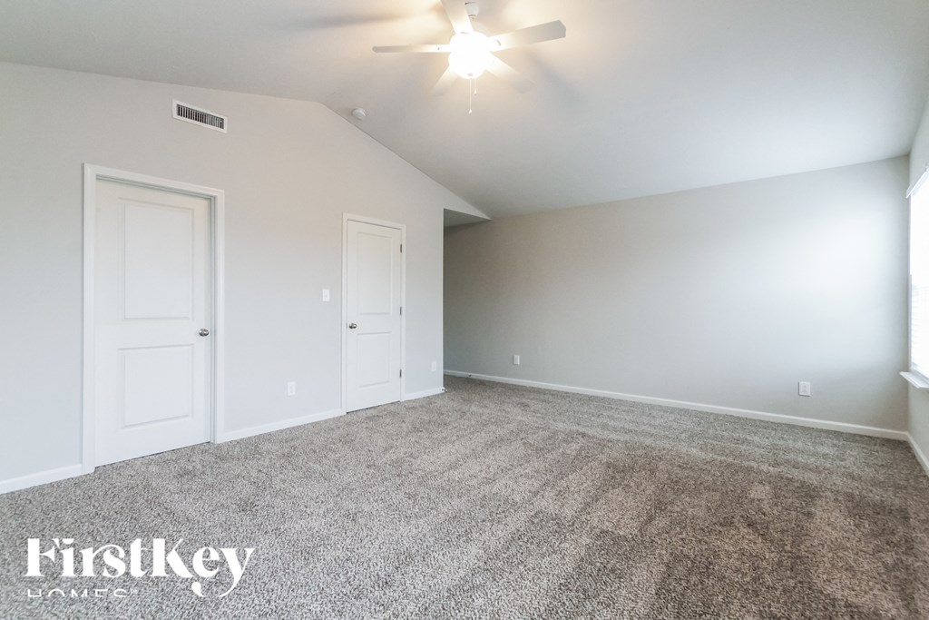 A room with a carpeted floor and two doors.
