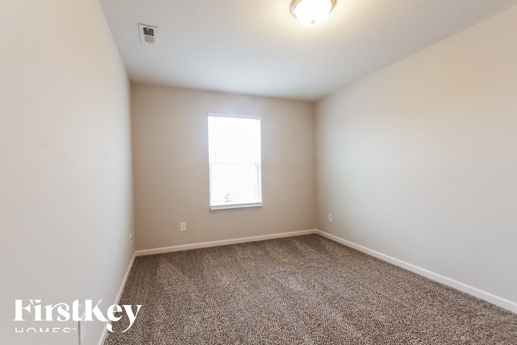 A room with a carpeted floor and a window letting in light.
