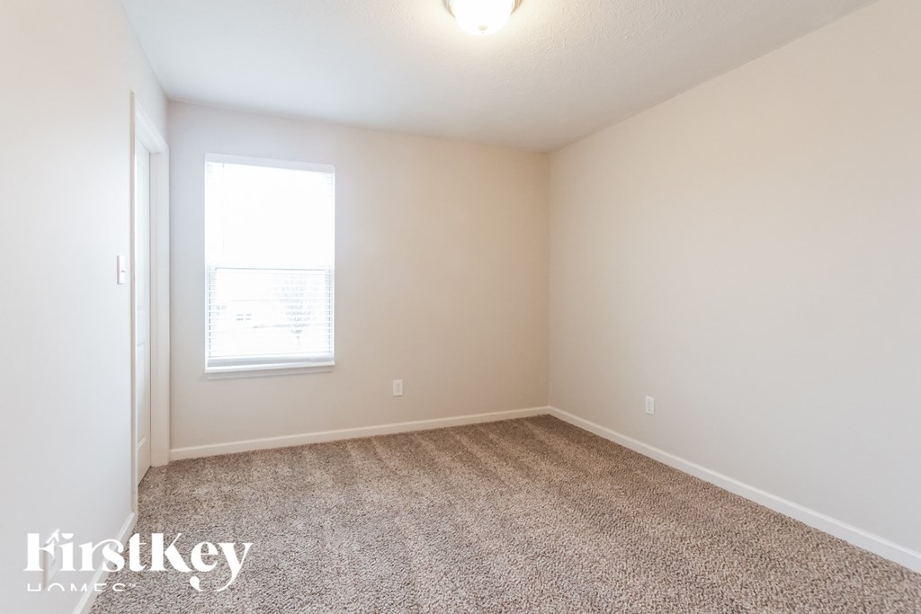 A room with a carpeted floor and a window letting in light.