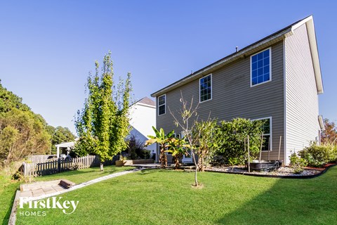 a side view of a house with a yard and trees