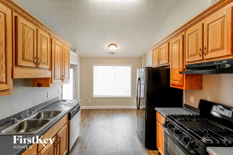 A kitchen with wooden cabinets and a black refrigerator.