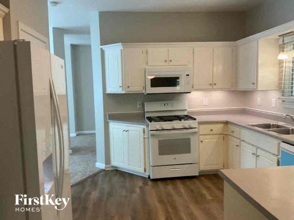 A kitchen with white cabinets and a wooden floor.