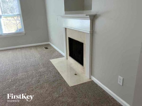A white fireplace in a room with a carpeted floor.