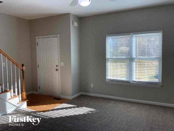 A room with a carpeted floor, a door, and a window with blinds.