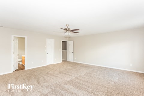 a spacious living room with carpet and a ceiling fan