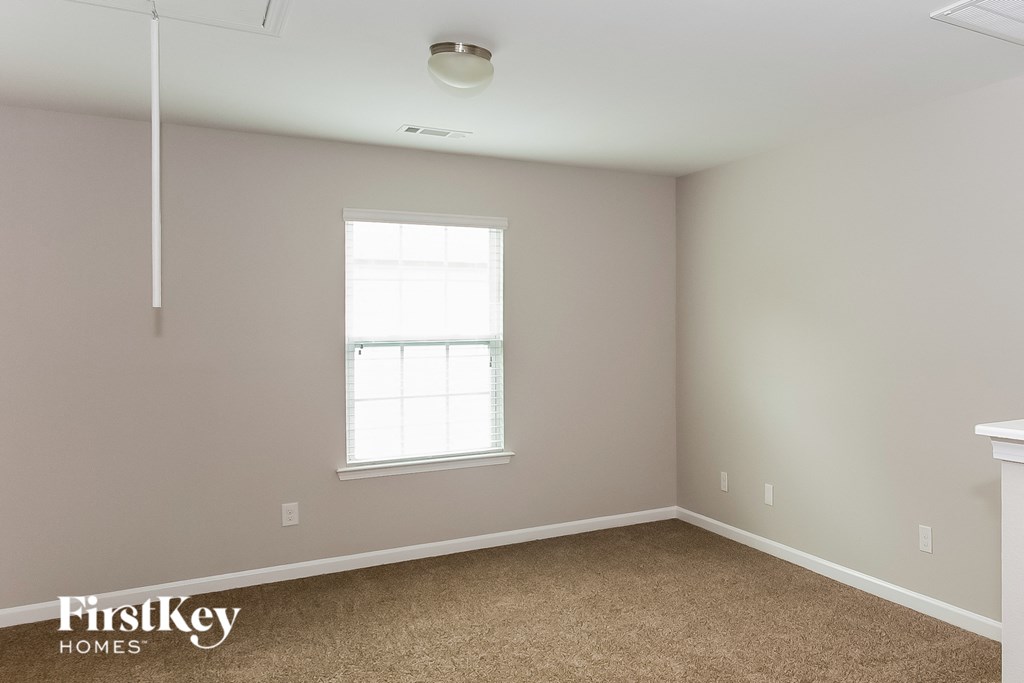 a bedroom with a window and a carpeted floor