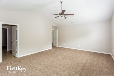 a spacious living room with carpet and a ceiling fan