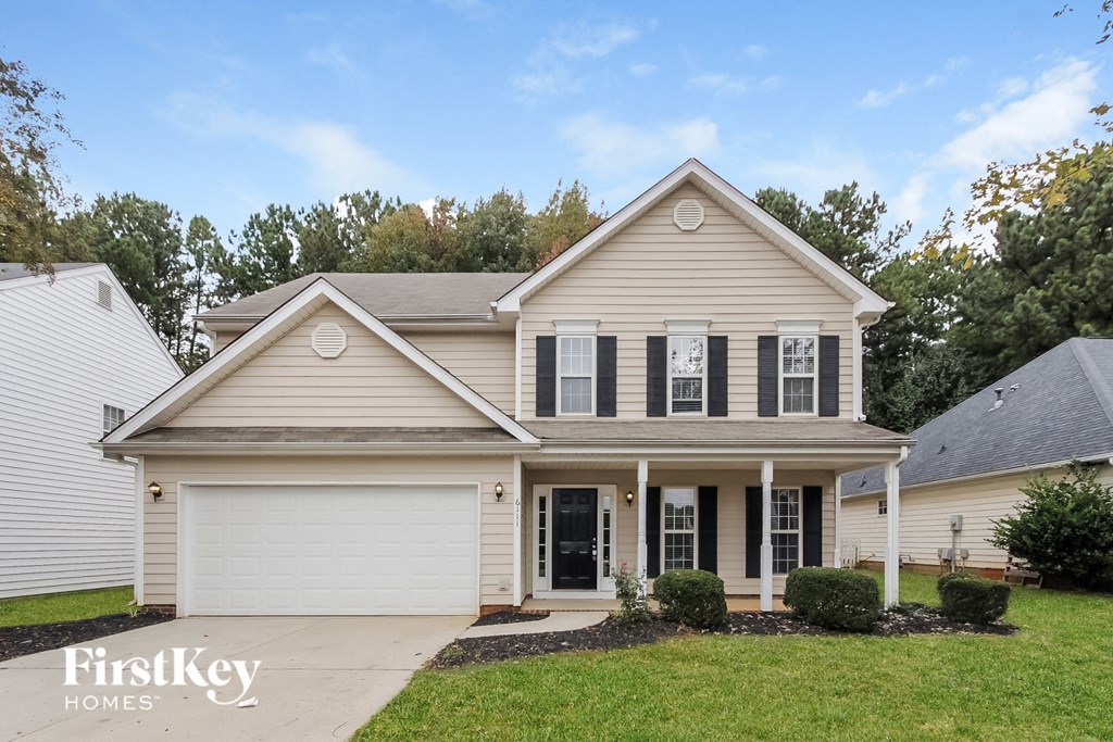 a beige house with black shutters and a lawn