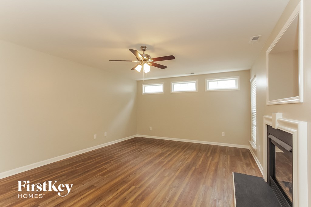 an empty living room with a ceiling fan and a fireplace