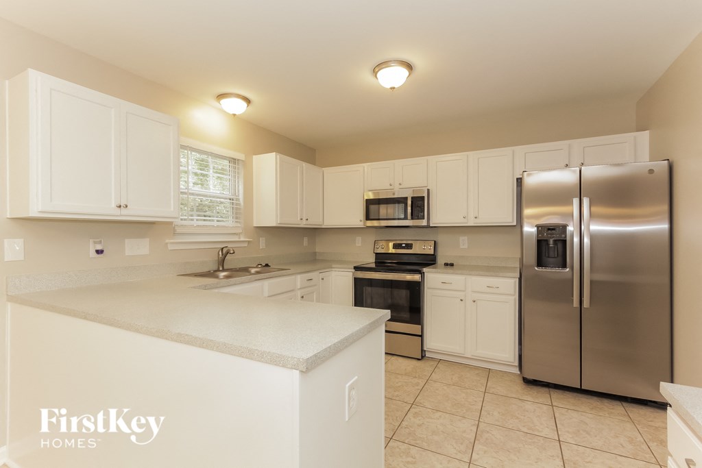 a white kitchen with stainless steel appliances and white cabinets