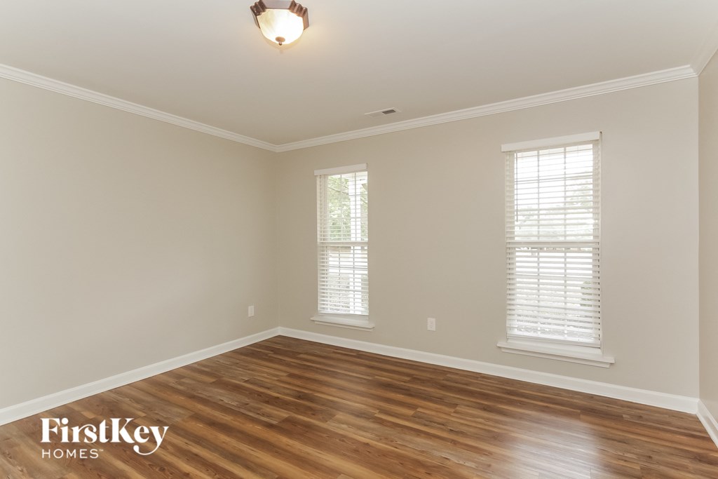 a living room with a hardwood floor and two windows