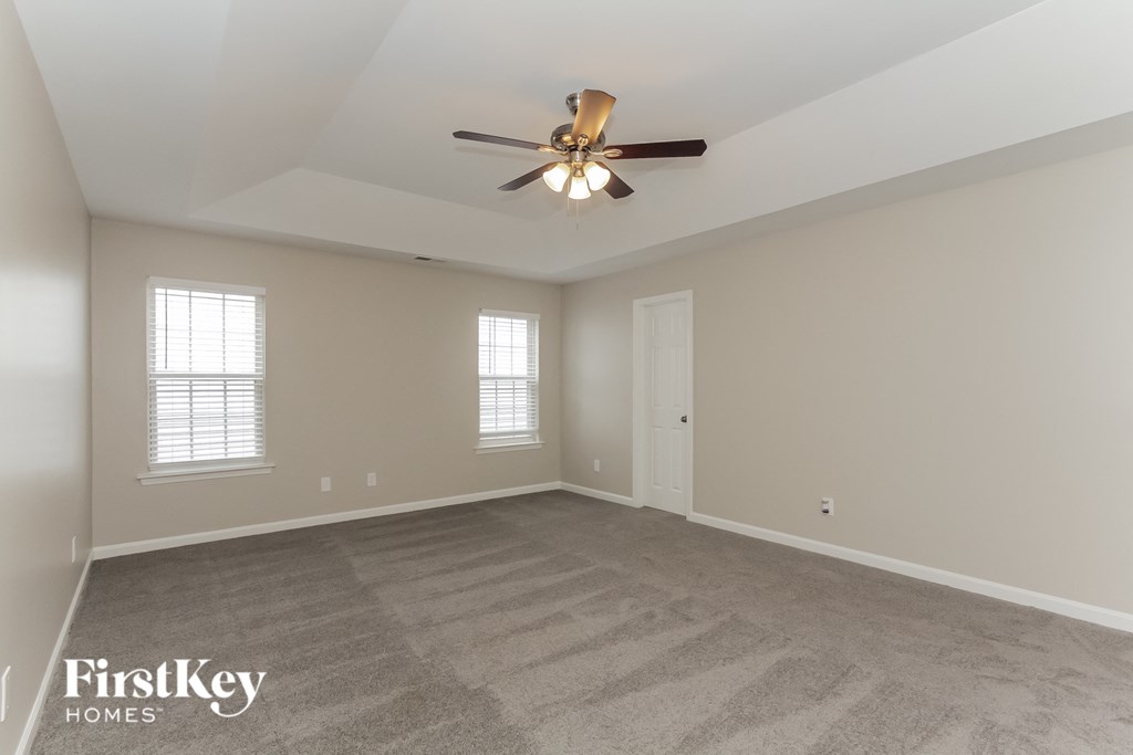 the spacious living room with ceiling fan and carpeting