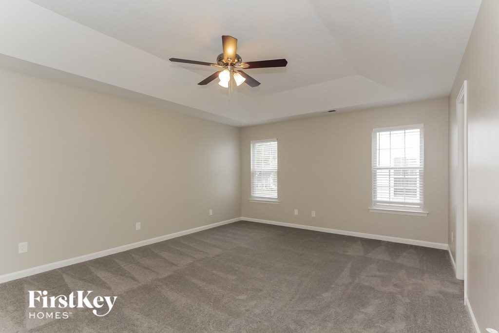 the spacious living room with ceiling fan and carpeting