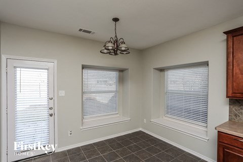 A room with a chandelier, two windows with blinds, and a door with a window.