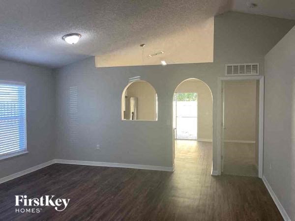 an empty living room with wood floors and a doorway
