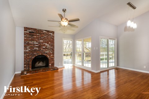 A living room with a brick fireplace and wood floors.