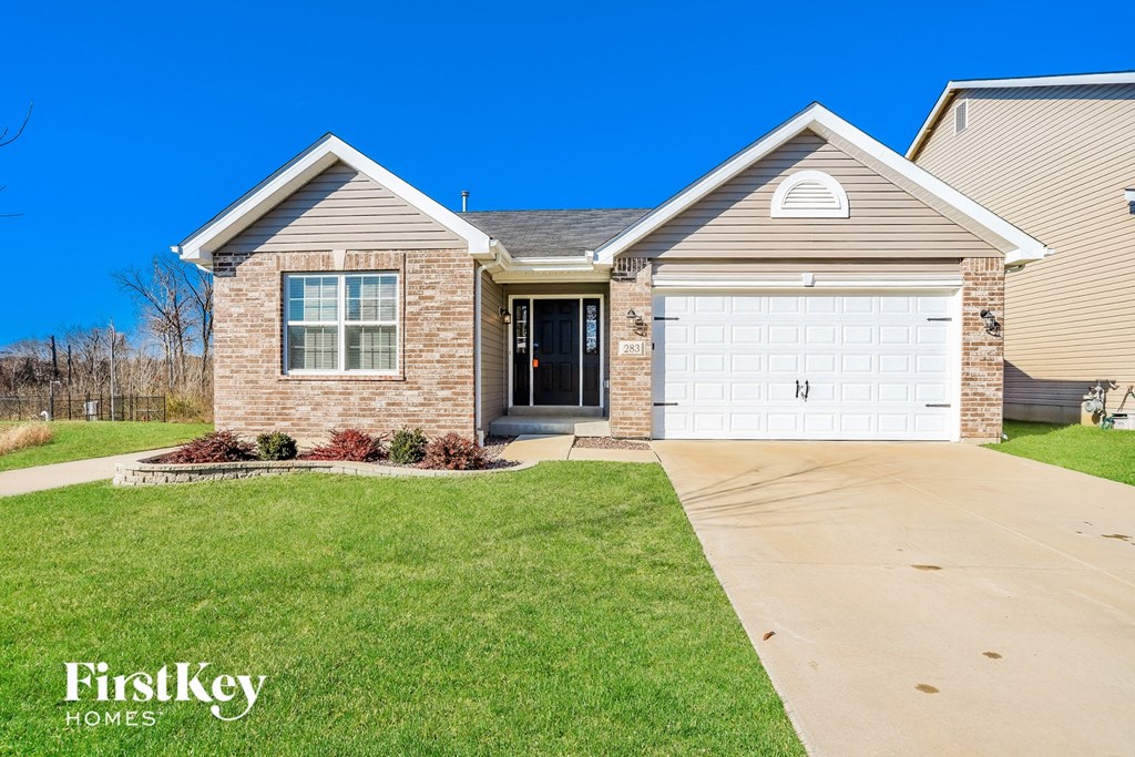 a brick house with a white garage door and a lawn