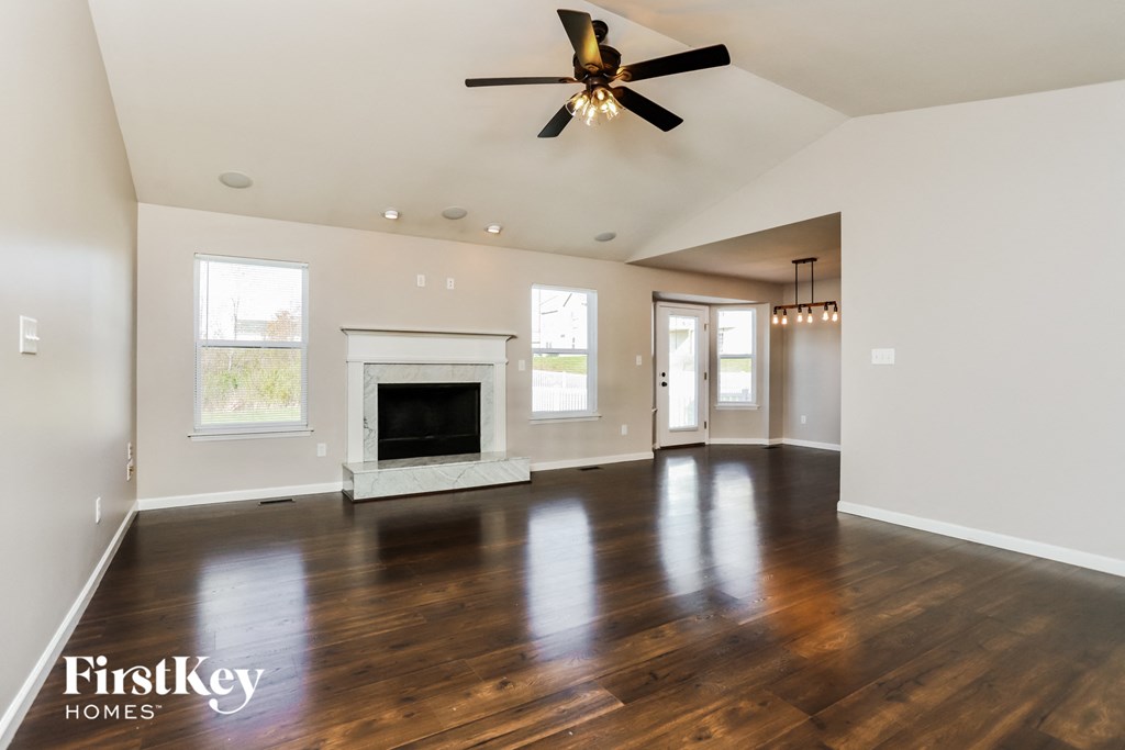 an empty living room with a fireplace and a ceiling fan