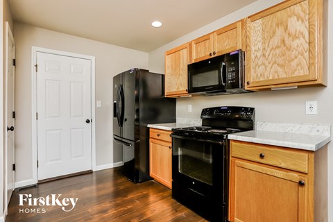 a kitchen with black appliances and wooden cabinets and a black refrigerator