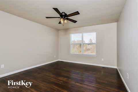 the master bedroom with hardwood flooring and a ceiling fan