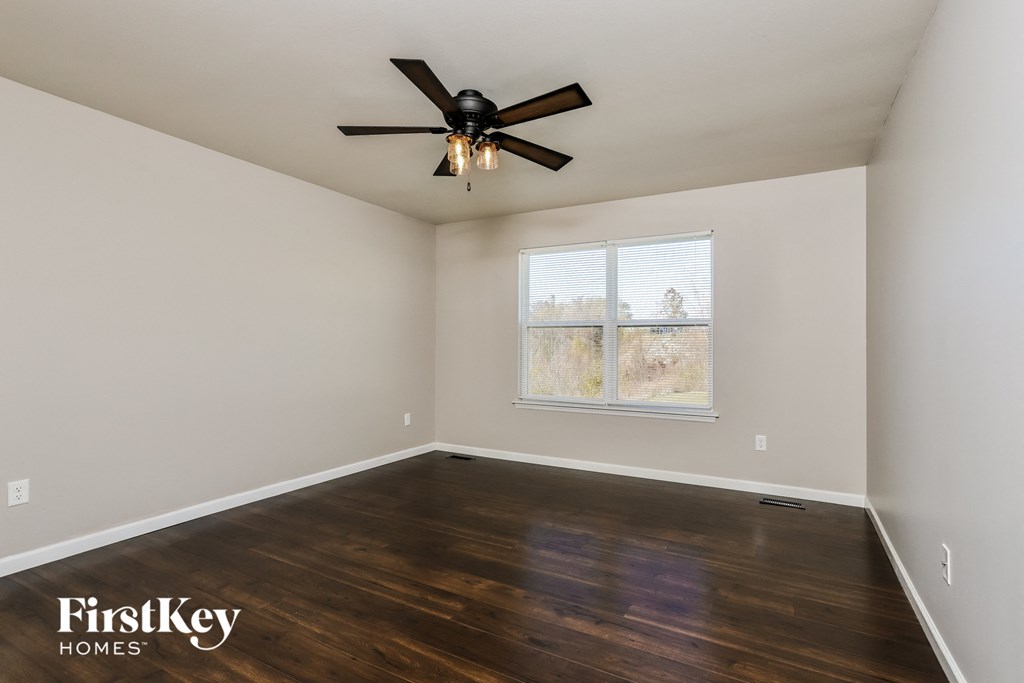 the master bedroom with hardwood flooring and a ceiling fan