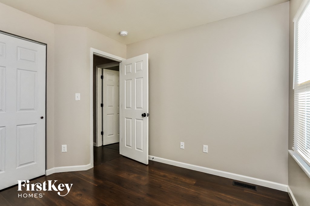 a bedroom with two doors and a door to the hallway and a closet