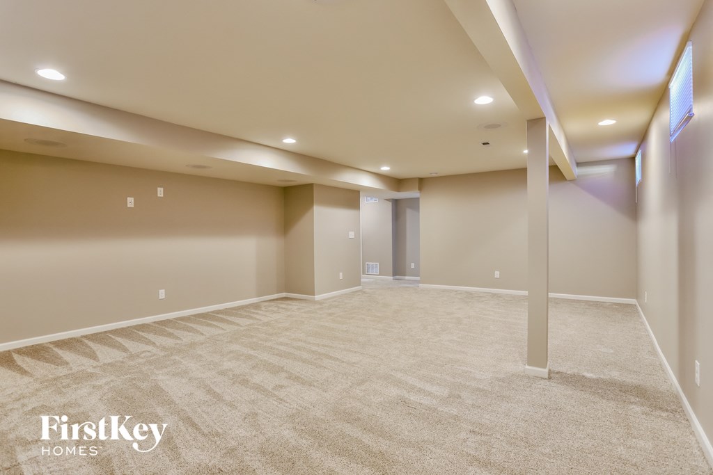 a empty basement with a carpeted floor and a wall mounted tv
