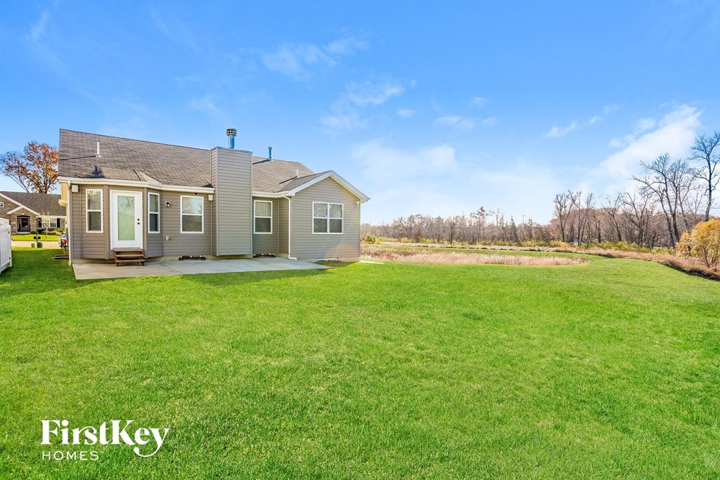 a small house with a yard and a grassy field