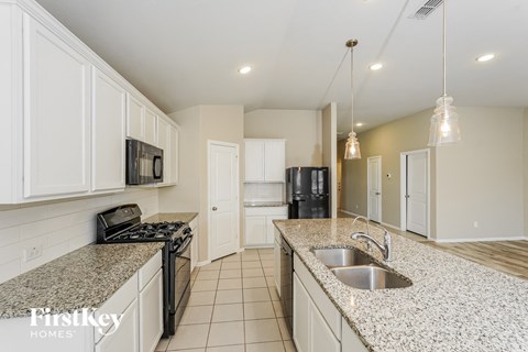 a kitchen with white cabinets and granite counter tops and a sink