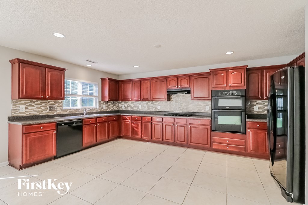 a kitchen with red cabinets and black appliances