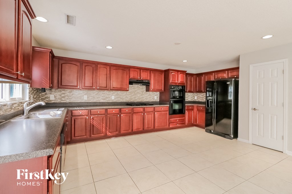 a large kitchen with red cabinets and black appliances