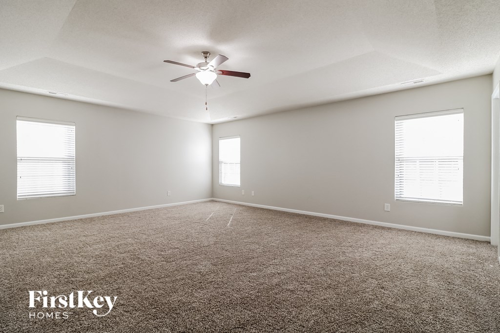 an empty living room with a ceiling fan and window