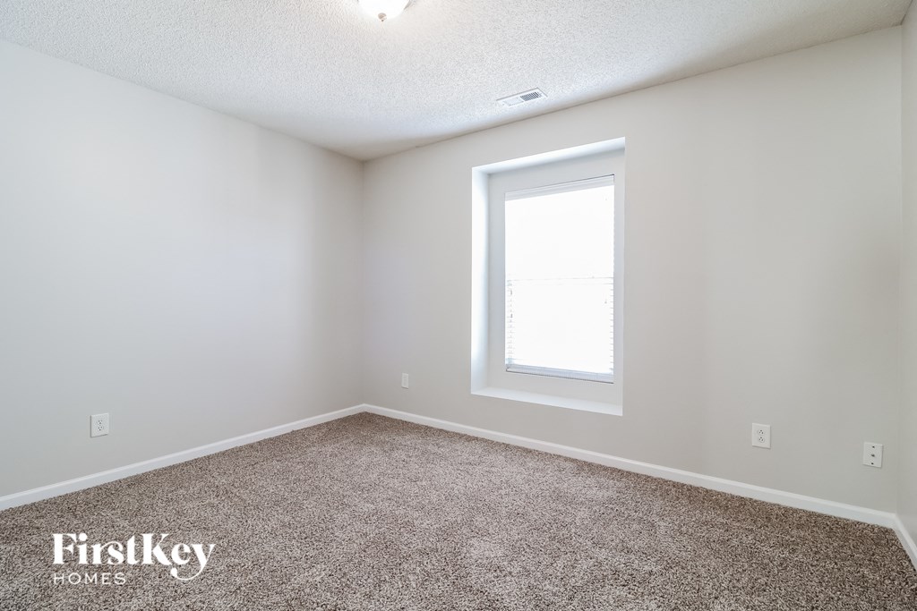 the spacious living room with carpeting and a window
