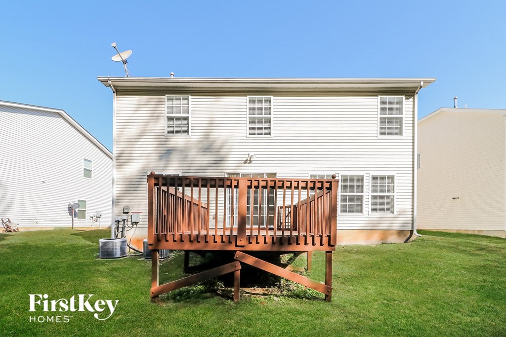 a backyard with a wooden deck and a white house