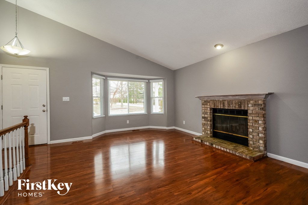 the living room of a house with a fireplace and wooden floors