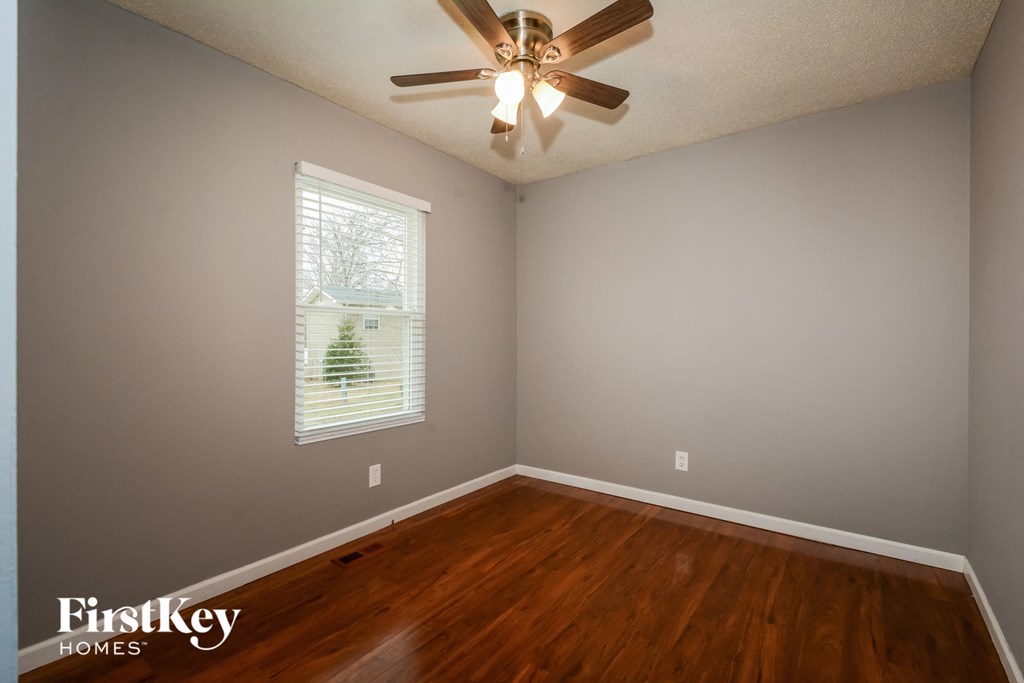 a bedroom with hardwood floors and a ceiling fan