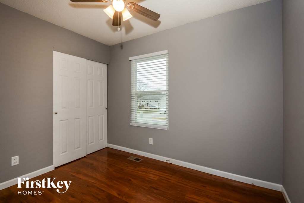 the bedroom with hardwood floors and a ceiling fan