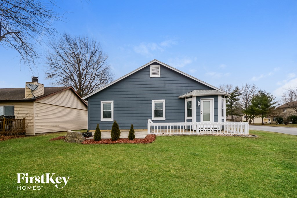 a blue house with a porch and a white fence