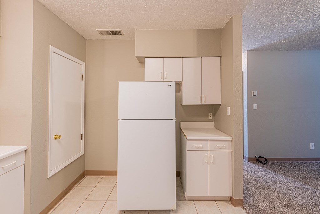 an empty kitchen with a white refrigerator and cabinets