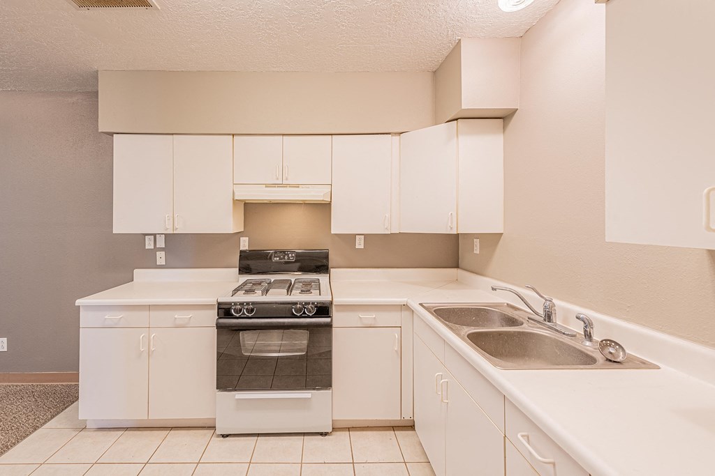 a kitchen with white cabinets and a stove and a sink