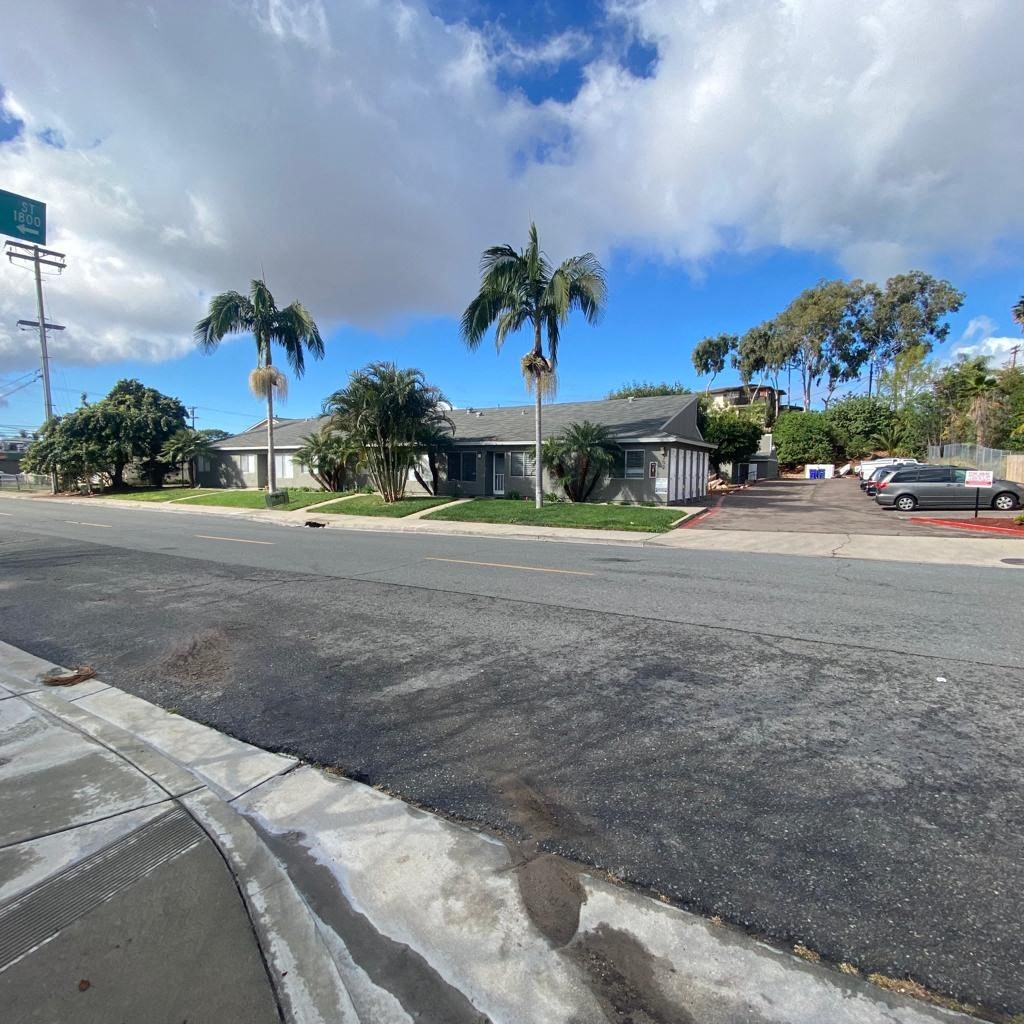 a house on the side of a street with palm trees