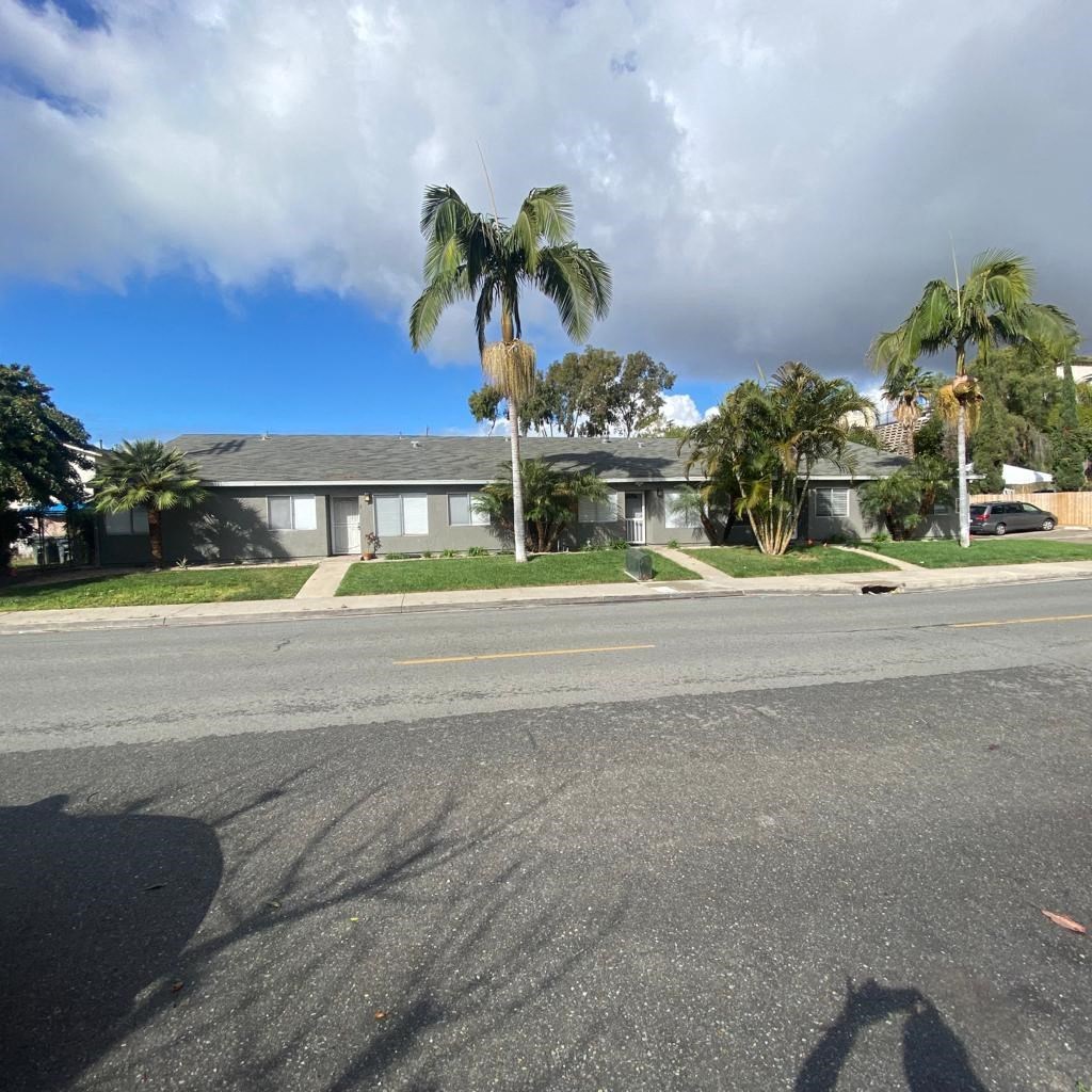 a house with palm trees on the side of a street