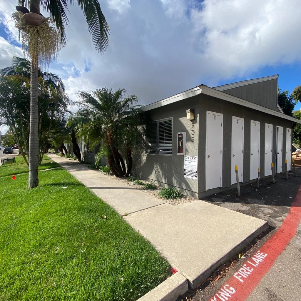 a small gray building with palm trees in front of it