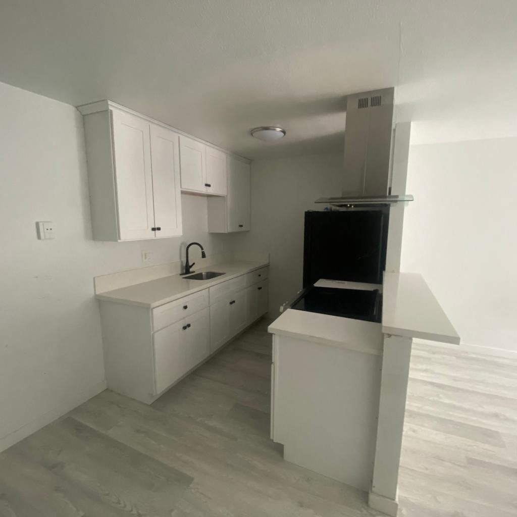 an empty kitchen with white cabinets and a black stove