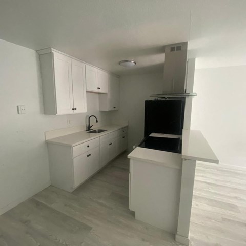an empty kitchen with white cabinets and a black stove